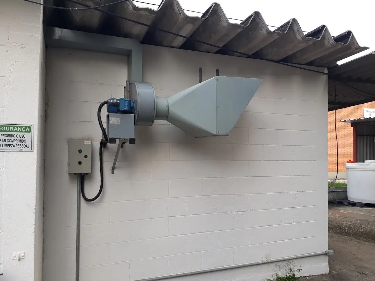 Exaustor axial com motor e captação instalado na parede externa de um galpão